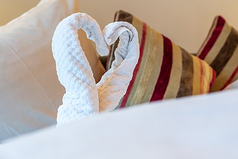 Detailaufnahme kunstvoll gefalteter Handtücher auf Bett